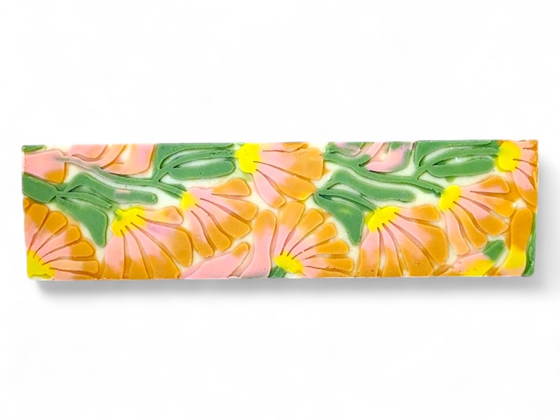 May include: A bar of soap with a floral design. The soap is white with pink, orange, and green flowers.