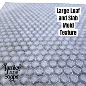 May include: A close-up of a grey honeycomb-patterned mold. The mold has a textured surface and is designed for large loaf and slab soap making. The text "Large Loaf and Slab Mold Texture" is visible. The Jamley Lane Soaps logo is in the lower left corner.