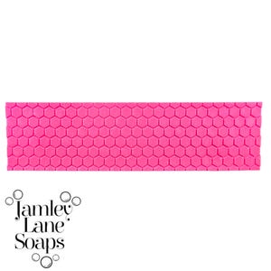 May include: A pink mold with a honeycomb pattern. The mold is designed for making soap or other crafts.