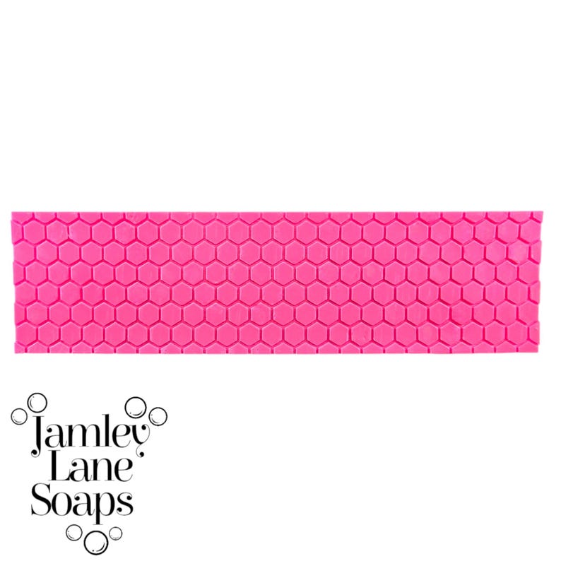 May include: A pink mold with a honeycomb pattern. The mold is designed for making soap or other crafts.