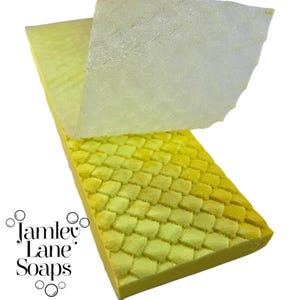 May include: A yellow soap bar with a textured, woven pattern. The soap is partially covered with a clear plastic sheet.