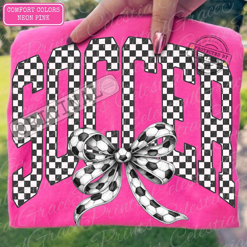 May include: Neon pink t-shirt with the word "SOCCER" in a black and white checkered pattern. A soccer ball bow is centered below the word. The shirt is labeled "COMFORT COLORS" and "NEON PINK".