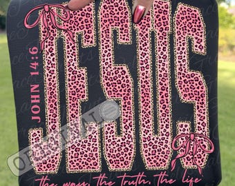 May include: Black sweatshirt with the word "JESUS" in pink leopard print outlined in gold. The text "JOHN 14:6" is on the left side, and "The way, the truth, the life" is at the bottom. Pink bows are on the top and bottom.