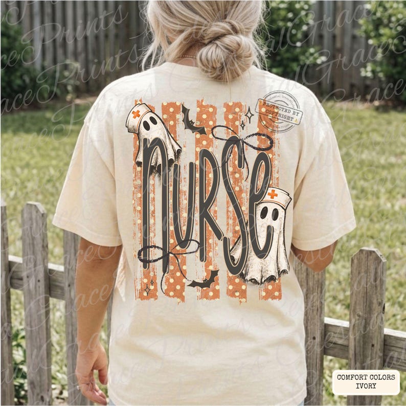 May include: An ivory short-sleeve t-shirt featuring a back graphic with the word nurse in large black script. The design includes two ghost figures wearing nurse caps, orange and white vertical stripes, small bats, and stars.