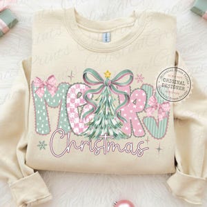 以下が含まれることがあります： クリーム色のスウェットシャツ。文字は「MERRY Christmas」で、遊び心のあるデザイン。文字はピンクとミントグリーンで、クリスマスツリーとリボンが描かれています。デザインには星と雪の結晶が含まれています。