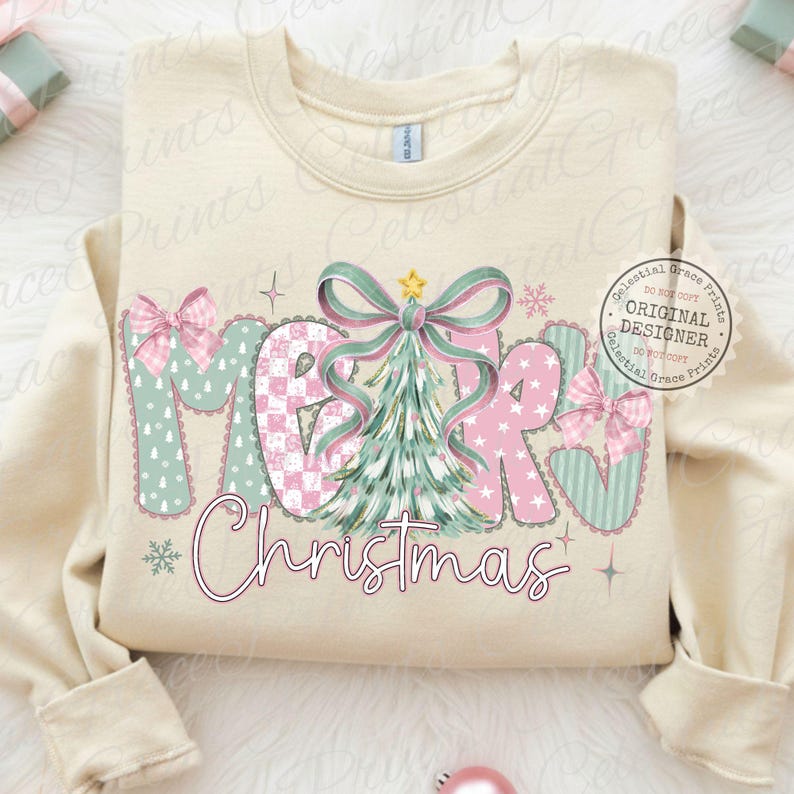 以下が含まれることがあります： クリーム色のスウェットシャツ。文字は「MERRY Christmas」で、遊び心のあるデザイン。文字はピンクとミントグリーンで、クリスマスツリーとリボンが描かれています。デザインには星と雪の結晶が含まれています。