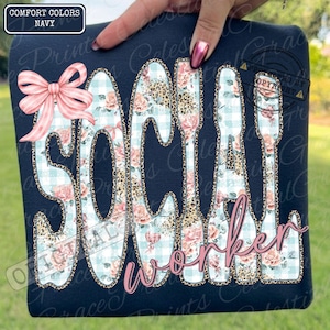 May include: Navy blue t-shirt with the words "SOCIAL WORKER" in a unique design. The letters are filled with floral, leopard print, and gingham patterns. A pink bow is on the left side of the shirt.