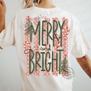 May include: An off-white short-sleeve t-shirt featuring a back graphic with the text MERRY and BRIGHT in dark green. The design includes red and white striped candy canes, green Christmas trees, and vertical red polka-dot stripes.