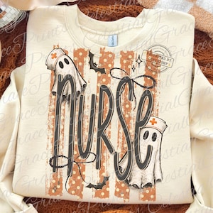 May include: A cream-colored crewneck sweatshirt featuring a graphic print with the word NURSE in large dark gray letters. The design includes two white ghosts wearing nurse caps, orange vertical stripes with white dots, and black bats.