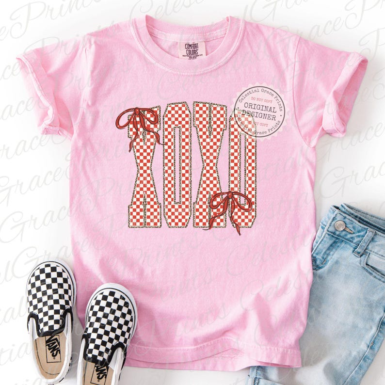 May include: A light pink t-shirt with the word "XOXO" in a red and white checkered pattern. The letters have red bows attached. A pair of black and white checkered slip-on shoes and a pair of blue jeans are also in the image.