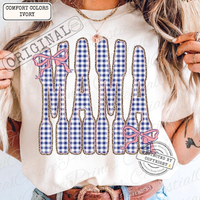 May include: Ivory t-shirt featuring the word "MAMA" in a blue and white gingham design, edged with leopard print. Pink bows decorate the design. The shirt has the text "Comfort Colors Ivory" in the upper left corner.