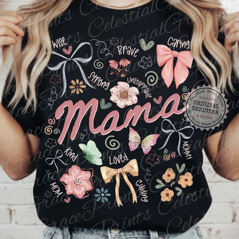 May include: Black t-shirt with the word "Mama" in pink script, surrounded by floral and bow graphics. Additional words like "Wise," "Brave," and "Caring" are also featured. The shirt has a round neckline.