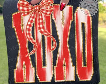 Puede incluir: Sudadera negra con las letras "XOXO" en rojo y blanco, contorneadas con purpurina dorada. Un lazo de cuadros rojos y blancos se coloca encima de las letras. Las palabras "Celestial Grace Prints" y "Original Designer" están impresas en la esquina superior derecha.
