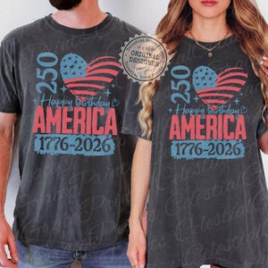Puede incluir: Camisetas de color gris oscuro con un dise&ntilde;o patri&oacute;tico. El dise&ntilde;o presenta una bandera estadounidense en forma de coraz&oacute;n, el texto "250 Happy Birthday AMERICA 1776-2026" en rojo y azul, celebrando el aniversario de la naci&oacute;n.