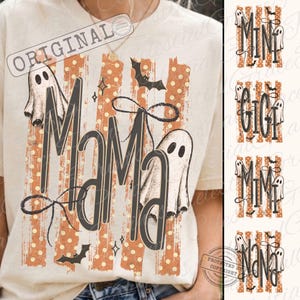 May include: A cream-coloured t-shirt featuring a graphic with the text MAMA in large dark letters. The design includes orange vertical stripes with white polka dots, two white ghost illustrations, black bats, and a thin black bow graphic.