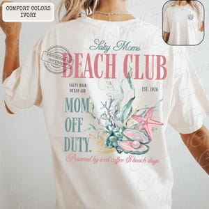 Puede incluir: Camiseta de color marfil con un dise&ntilde;o de tem&aacute;tica playera. El dise&ntilde;o incluye el texto "Salty Moms Beach Club" con ilustraciones de una estrella de mar, una concha y plantas acu&aacute;ticas. La camiseta tambi&eacute;n tiene el texto "Mom Off Duty".