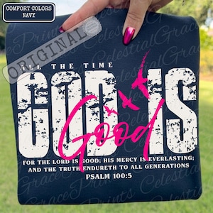 May include: Navy blue Comfort Colors t-shirt with the words "GOD IS GOOD" in distressed white and pink lettering. The shirt also features the text "ALL THE TIME" and Psalm 100:5. A design of pink birds is also included.