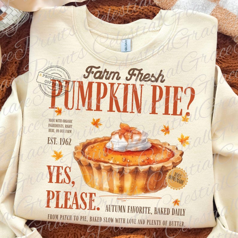 May include: A cream-colored crewneck sweatshirt featuring a graphic of a pumpkin pie with whipped cream. Text reads: Farm Fresh PUMPKIN PIE? EST. 1962, YES, PLEASE. AUTUMN FAVORITE, BAKED DAILY, MADE WITH ORGANIC INGREDIENTS, RIGHT HERE, ON OUR FARM.