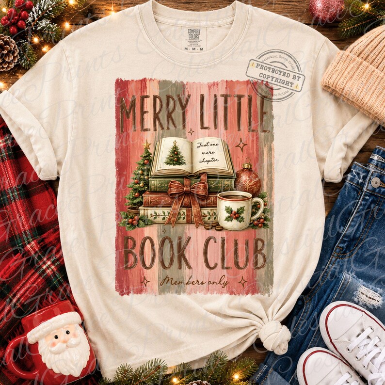 May include: A cream-colored short-sleeve t-shirt featuring a graphic of a stack of books, a Christmas tree, and a mug. The text reads MERRY LITTLE BOOK CLUB, Just one more chapter, and Members only. The design includes red and green holiday accents.