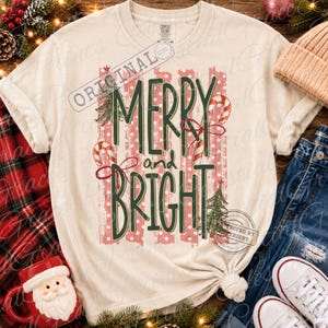 May include: A cream-colored short-sleeve t-shirt featuring the text MERRY and BRIGHT in dark green letters. The design includes red and white candy canes, green Christmas trees, and a background of vertical red and white polka-dot stripes.