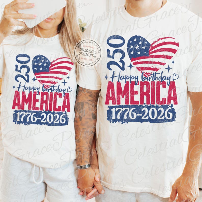 Puede incluir: Dos camisetas blancas con un dise&ntilde;o patri&oacute;tico. El dise&ntilde;o presenta una bandera estadounidense en forma de coraz&oacute;n, el texto "250 Happy Birthday AMERICA 1776-2026" en rojo y azul, y estrellas. Las camisetas son usadas por dos personas.