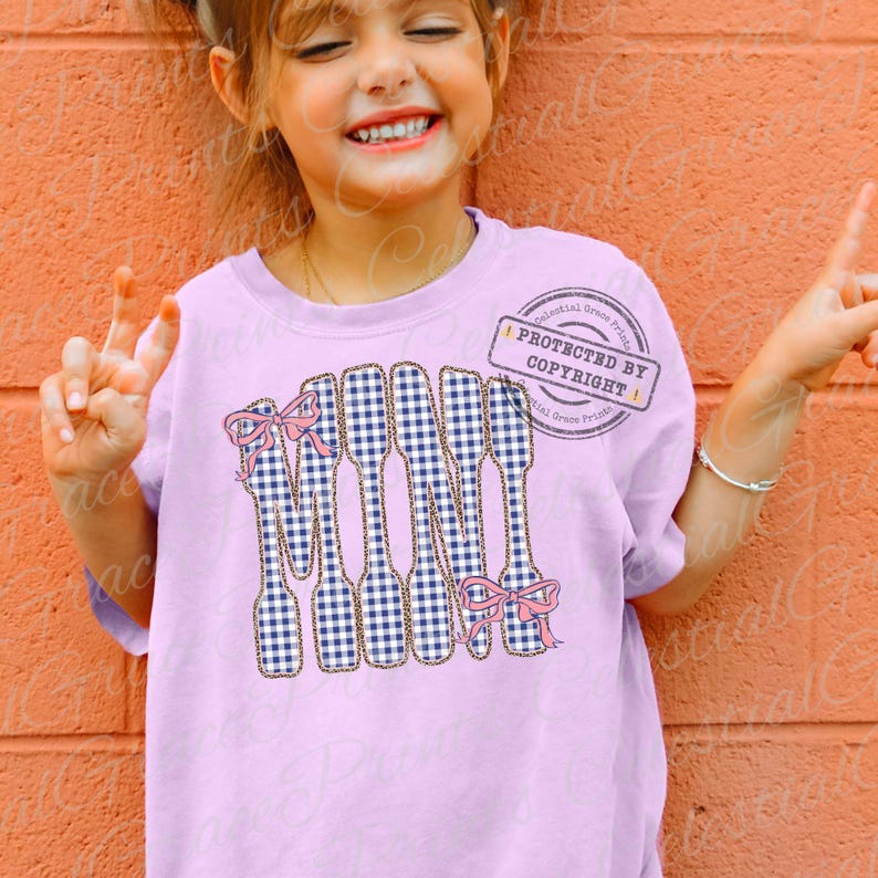 May include: A lilac t-shirt with a design of spoons in a blue and white gingham pattern. Each spoon has a pink bow. The word "MOM" is spelled out with the spoons. A copyright stamp is visible.