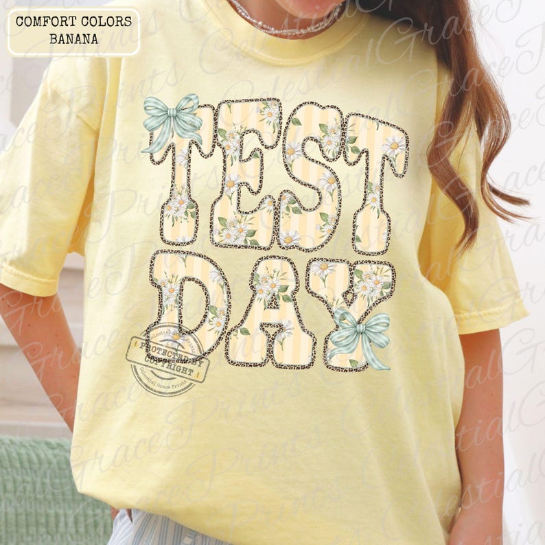 Peut inclure: Un t-shirt jaune clair avec les mots "TEST DAY" dans un motif floral et ray&eacute;. Les lettres sont soulign&eacute;es d'un motif l&eacute;opard. Le t-shirt comporte &eacute;galement deux n&oelig;uds bleu clair.