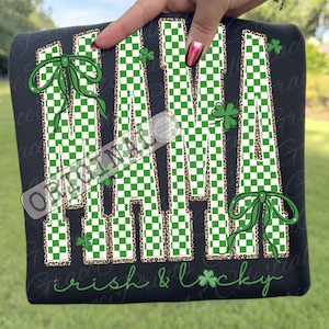 Puede incluir: Sudadera negra con la palabra "MAMA" en un patrón de cuadros verdes y blancos, detalles de estampado de leopardo, lazos verdes y tréboles. El texto "Irish & Lucky" está impreso en la parte inferior.