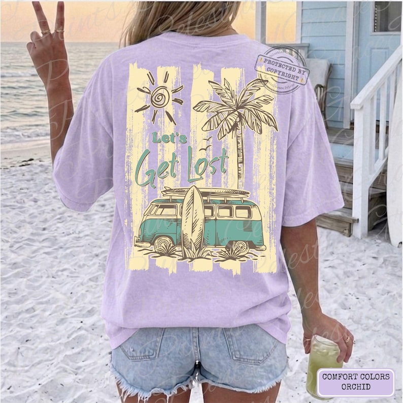 May include: Orchid-colored t-shirt with a beach-themed graphic. The design features a sun, palm tree, and a teal and white van with a surfboard. The text "Let's Get Lost" is in teal script. The shirt is a Comfort Colors brand.