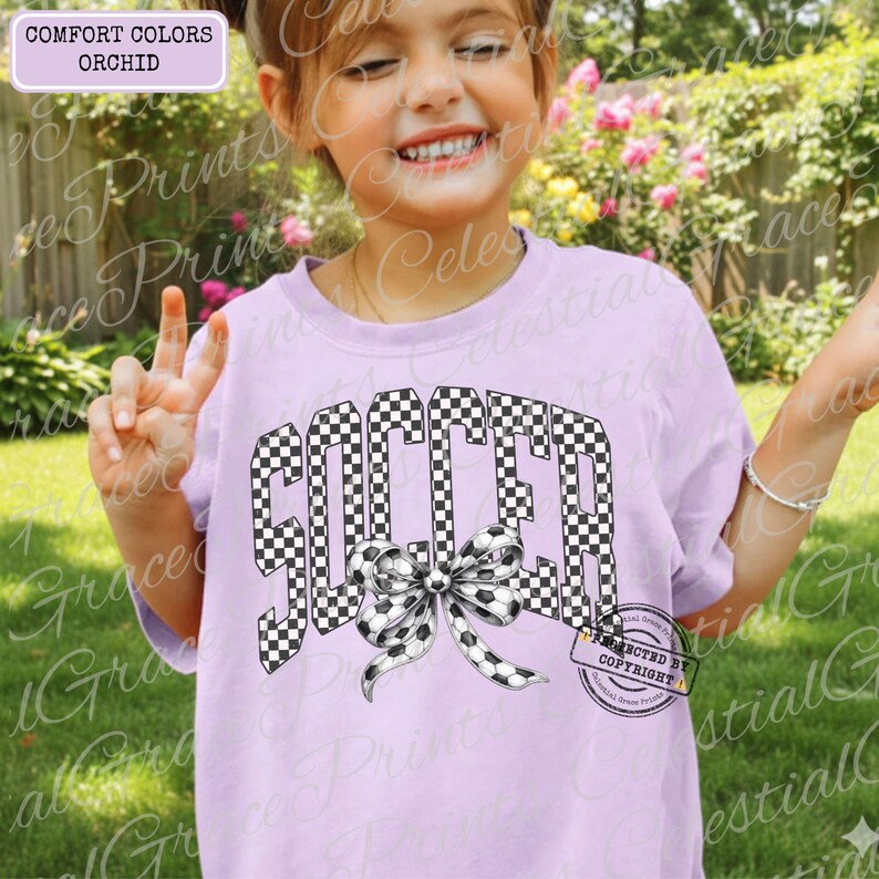 May include: A light purple t-shirt with the word "SOCCER" in a black and white checkered pattern. A bow made of soccer balls is below the word. The shirt also has the text "COMFORT COLORS ORCHID" in a box.