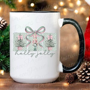 May include: White ceramic mug with a black handle and rim, featuring a Christmas design. The design includes a bow, Christmas trees, a nutcracker, and the words "holly jolly". The mug is decorated with pink, green, and white colours.