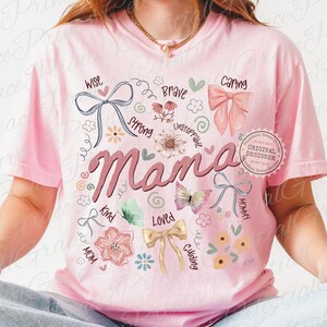 May include: Pink t-shirt with the word "Mama" in a cursive font, surrounded by floral and bow graphics. Additional words like "Wise," "Caring," and "Loved" are also featured. The design includes butterflies and a "Original Designer" stamp.