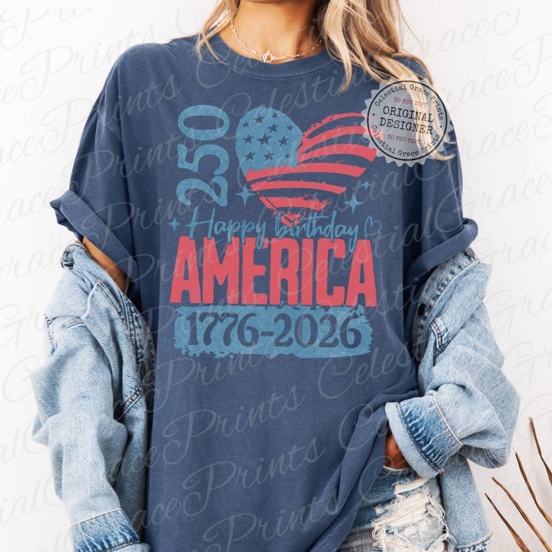 Puede incluir: Camiseta azul marino con un dise&ntilde;o patri&oacute;tico. La camiseta presenta una bandera estadounidense en forma de coraz&oacute;n, el texto "250 Happy Birthday AMERICA 1776-2026" y un logotipo de "Celestial Grace Prints". Se usa con una chaqueta vaquera.