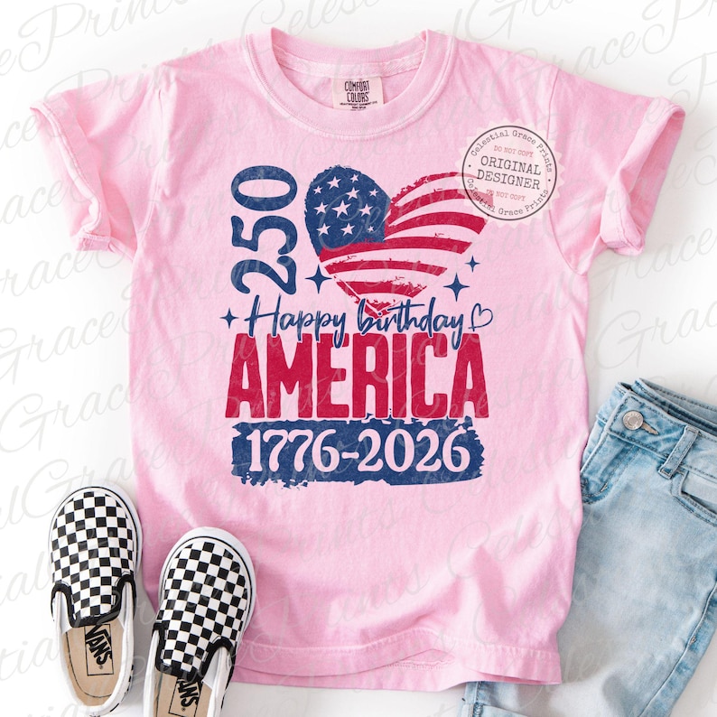 Puede incluir: Una camiseta rosa claro con el texto "250 Happy Birthday AMERICA 1776-2026" y un dise&ntilde;o de bandera americana en forma de coraz&oacute;n. La camiseta se muestra con zapatos sin cordones a cuadros y vaqueros azules.