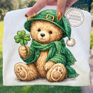 May include: A teddy bear illustration wearing a green hat, scarf, and jacket, holding a four-leaf clover. The bear has brown fur and is sitting. The image includes the text "Celestial Grace Prints" and "Original Designer".