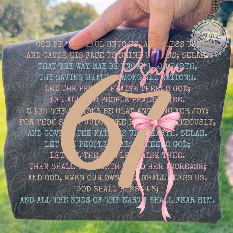 May include: Dark gray t-shirt with Psalm 67 scripture text in pink and teal. A large tan number 67 is centered, with a pink bow. The words "Celestial Grace Prints" are also visible.