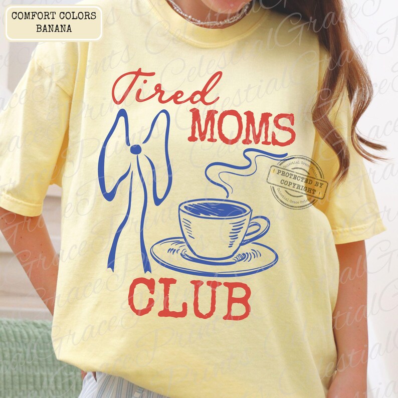 May include: A light yellow t-shirt with the words "Tired MOMS CLUB" in red and blue. A blue bow and a coffee cup with steam are also featured in the design. The shirt is labeled "COMFORT COLORS BANANA".