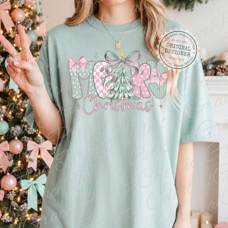 以下が含まれることがあります： 「MERRY Christmas」の文字がデザインされた、明るい緑色のTシャツ。文字はピンクと緑の模様、リボン、クリスマスツリーで装飾されています。快適でカジュアルなスタイルです。