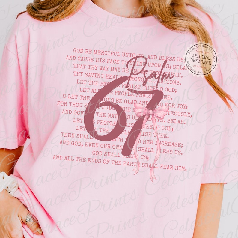 May include: A light pink t-shirt featuring the text "Psalm 67" in a large, stylized font, with a pink bow. The shirt also has a printed passage of text. A circular "Original Designer" sticker is visible.