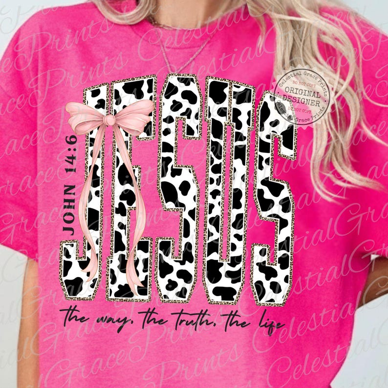 Puede incluir: Camiseta rosa intenso con la palabra "JESUS" en un dise&ntilde;o de letras en bloque audaz. Las letras presentan un patr&oacute;n de vaca con un borde de estampado de leopardo. Un lazo rosa y el texto "JOHN 14:6" est&aacute;n en el lado izquierdo. La frase "the way, the truth, the life" est&aacute; en la parte inferior.