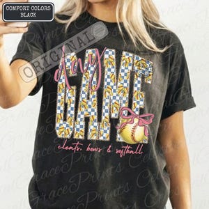 May include: Black t-shirt with "GAME DAY" in pink script and a checkered pattern. The design includes a softball with a pink bow and the words "cleats, bows & softball". The shirt has a vintage look.