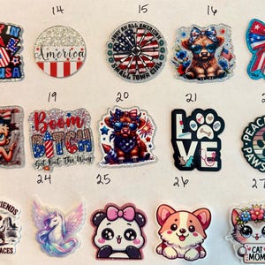 May include: A collection of fifteen decorative stickers featuring various designs including patriotic themes with American flags, cartoon animals like a highland cow, a corgi, and a cat, plus text such as Party in the USA, Boom Bitch, and Cat Mom.