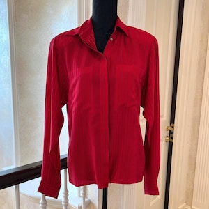 May include: A red striped long-sleeve button-up shirt with a collar and a pocket on the left side.