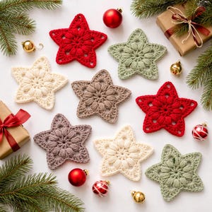 May include: A collection of eight crocheted star ornaments in red, cream, sage green, and taupe. The stars feature a textured puff stitch center and openwork points. They are arranged with small red and gold baubles and wrapped gift boxes.