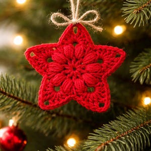 May include: A bright red crocheted star ornament featuring a textured puff stitch center and openwork points. The star is suspended by a thin, natural-colored jute twine string tied in a small bow at the top, hanging from a green pine tree branch.
