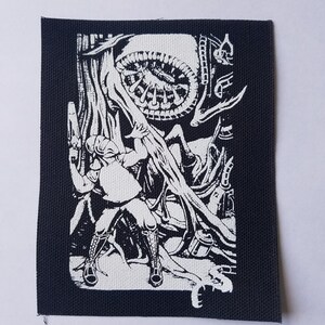 May include: Black and white embroidered patch depicting a person holding a weapon and facing a large, circular, alien-like creature with tentacles.