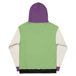 Puede incluir: Una sudadera con capucha verde, blanca y morada con una banda negra. La sudadera tiene una capucha grande y mangas largas.