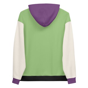 Puede incluir: Una sudadera con capucha verde, blanca y morada. La sudadera tiene una banda negra en la cintura.