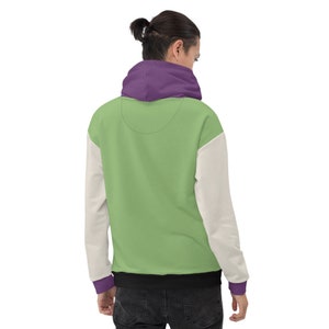 Puede incluir: Una sudadera con capucha de color verde, blanco y morado con una banda negra.