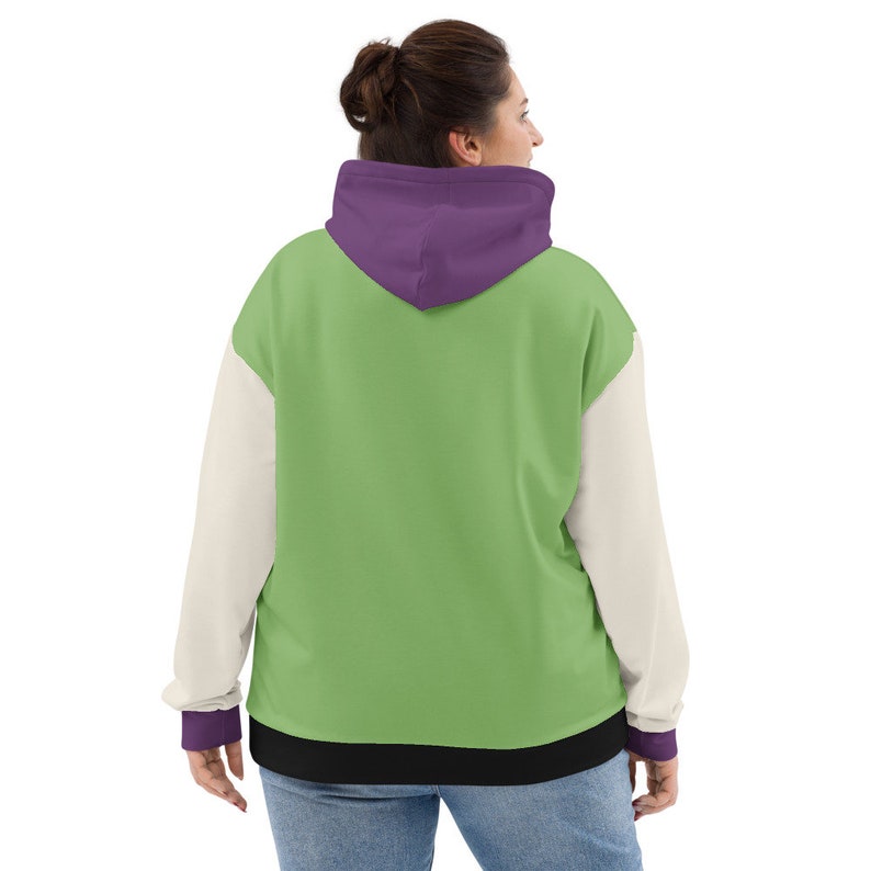 Puede incluir: Una sudadera con capucha verde, blanca y morada con una banda negra. La sudadera tiene una capucha con un forro morado.
